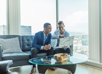 two men in suit sitting on sofa