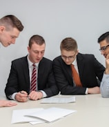 four men looking to the paper on table