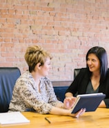 two women sitting on leather chairs in front of table