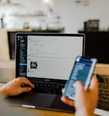 person using phone and laptop